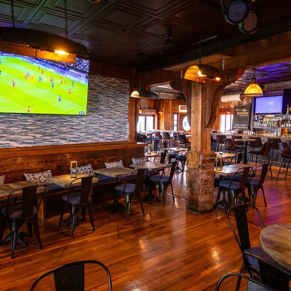 Spacious restaurant interior with dining tables, a long bar, and multiple TVs showing sports.